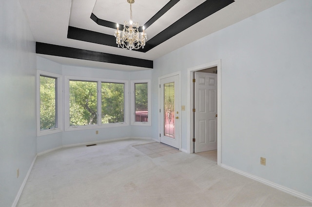 carpeted spare room with a tray ceiling, visible vents, baseboards, and an inviting chandelier