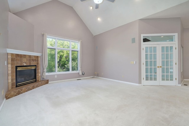 unfurnished living room featuring high vaulted ceiling, carpet floors, baseboards, french doors, and a tiled fireplace