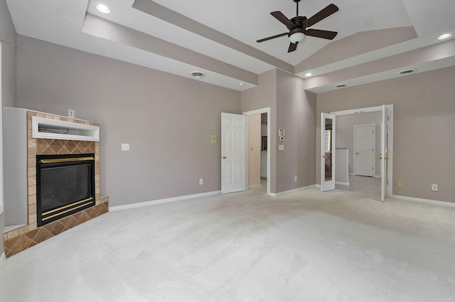 unfurnished living room featuring light carpet, visible vents, baseboards, a tray ceiling, and a fireplace