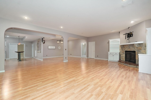 unfurnished living room featuring light wood-style floors, recessed lighting, baseboards, and a stone fireplace