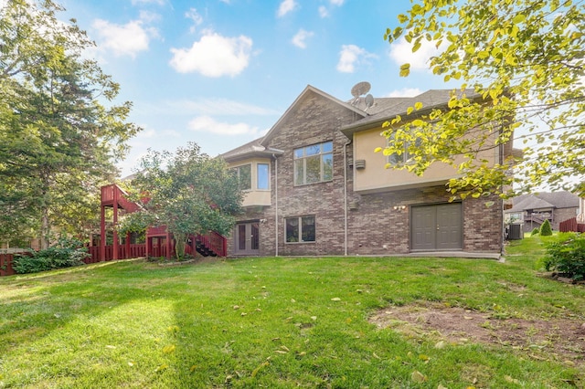 rear view of property with stucco siding, fence, cooling unit, a yard, and brick siding