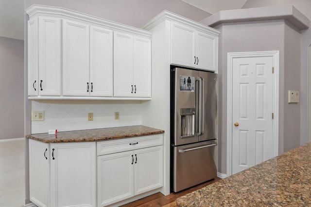 kitchen with dark stone counters, wood finished floors, high end fridge, white cabinetry, and backsplash