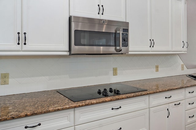 kitchen with white cabinetry, stainless steel microwave, and black electric cooktop