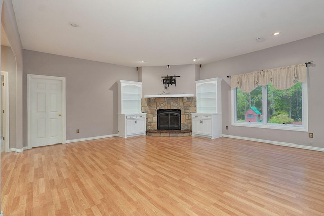 unfurnished living room with light wood-style floors, recessed lighting, a stone fireplace, and baseboards