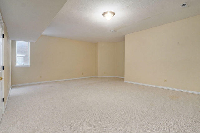 spare room featuring baseboards, a textured ceiling, visible vents, and light colored carpet