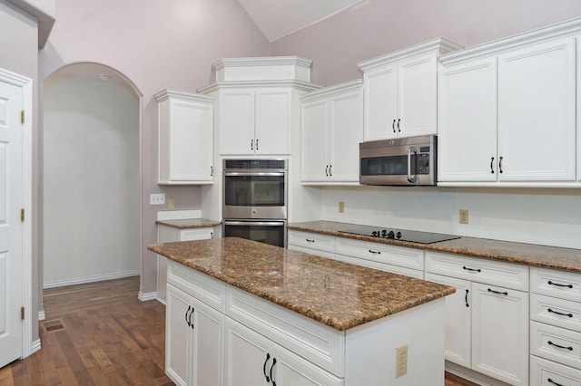 kitchen with dark wood-type flooring, white cabinetry, vaulted ceiling, appliances with stainless steel finishes, and tasteful backsplash