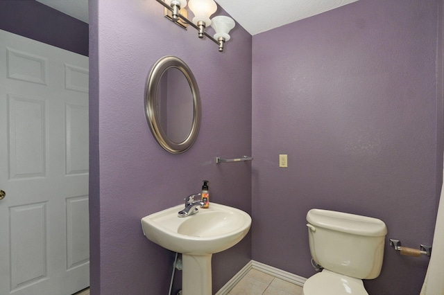 bathroom with baseboards, toilet, and tile patterned floors