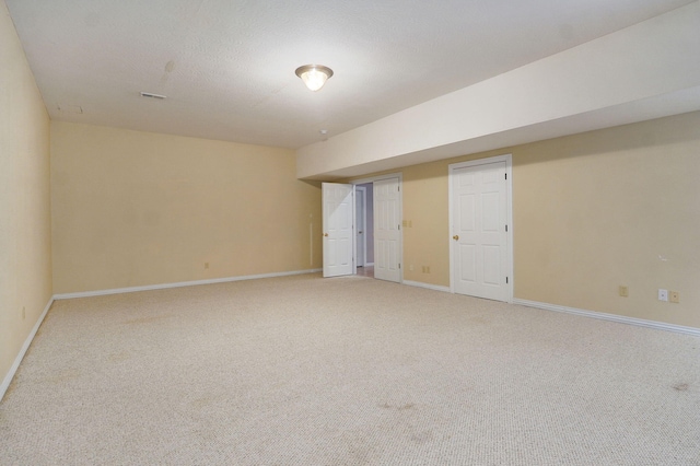 unfurnished room with light carpet, baseboards, and a textured ceiling