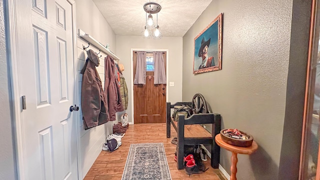 interior space featuring wood finished floors, a textured ceiling, and a textured wall