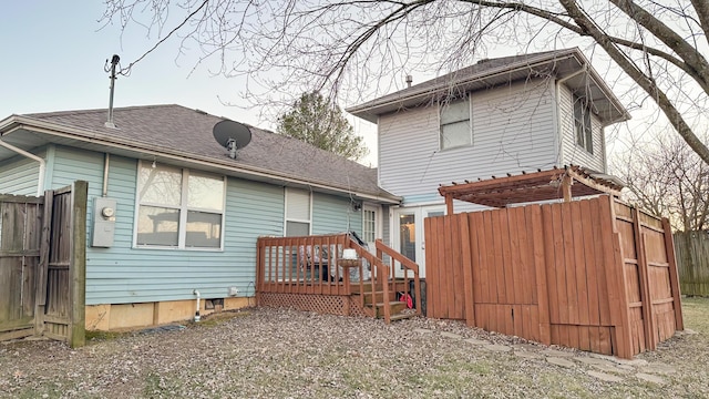 rear view of property with fence, a deck, and roof with shingles