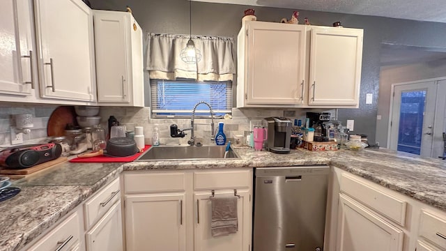 kitchen with stainless steel dishwasher, decorative backsplash, a sink, and white cabinets