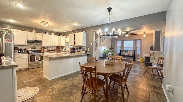 kitchen with under cabinet range hood, a peninsula, baseboards, hanging light fixtures, and appliances with stainless steel finishes