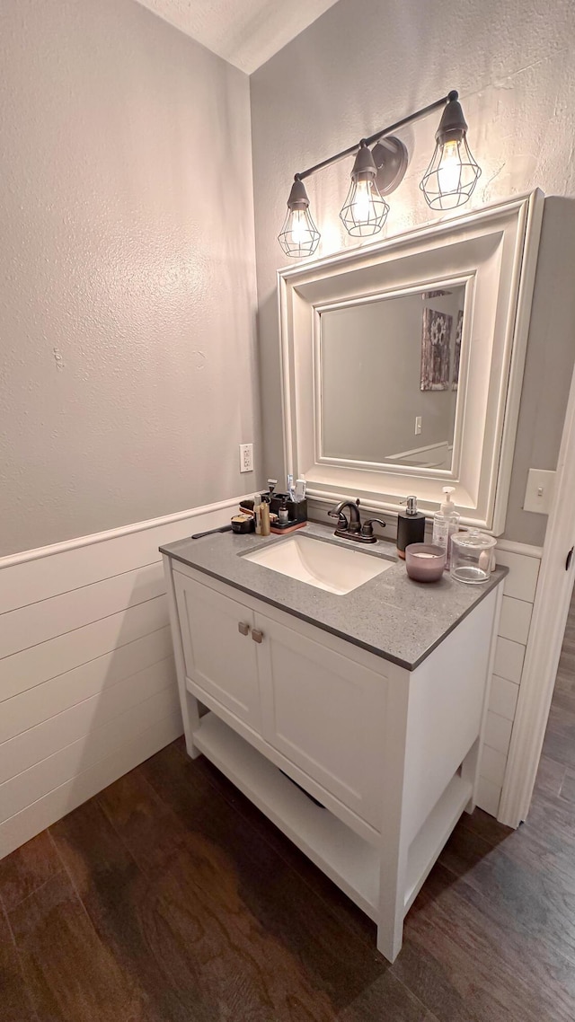 bathroom with a wainscoted wall, vanity, and wood finished floors