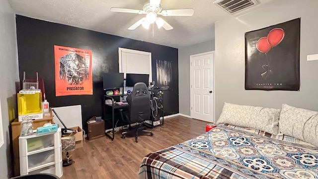 bedroom with baseboards, visible vents, ceiling fan, wood finished floors, and a textured ceiling