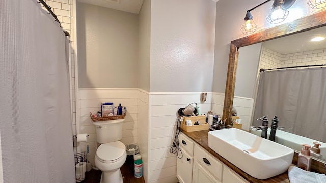 bathroom featuring a wainscoted wall, vanity, toilet, and a shower with curtain