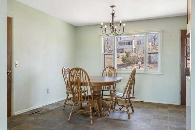 dining area featuring a chandelier, stone finish floor, visible vents, and baseboards