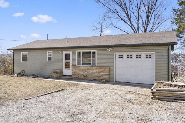 ranch-style house featuring a garage, stone siding, driveway, and roof with shingles