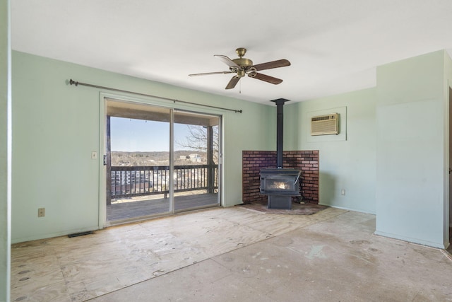 unfurnished living room with a wood stove, a wall unit AC, visible vents, and a ceiling fan