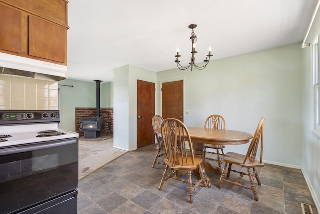 dining space with baseboards, visible vents, a wood stove, stone finish flooring, and a notable chandelier