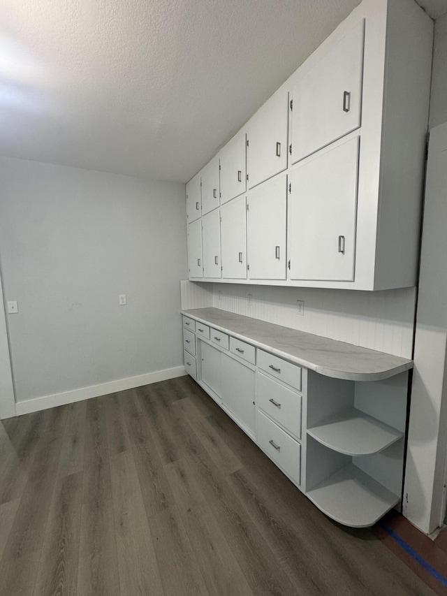 unfurnished office featuring dark wood-style floors, a textured ceiling, and baseboards