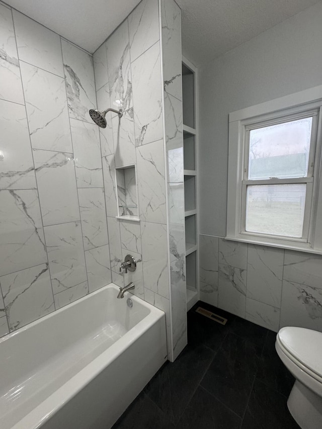 bathroom featuring marble finish floor, a wainscoted wall, tile walls, bathing tub / shower combination, and toilet