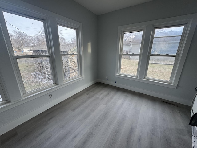 spare room with visible vents, baseboards, and wood finished floors