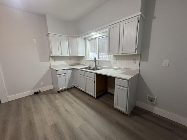 kitchen featuring baseboards, light countertops, a sink, and wood finished floors