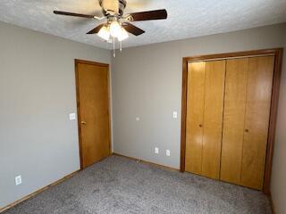 unfurnished bedroom featuring a textured ceiling, ceiling fan, a closet, and carpet