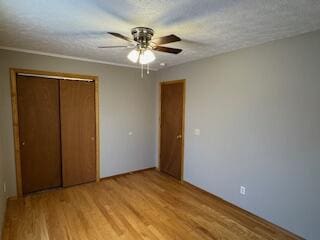 unfurnished bedroom featuring light wood-style floors, a closet, ceiling fan, and a textured ceiling