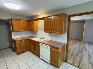 kitchen featuring dishwasher, a sink, and brown cabinets