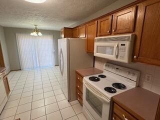 kitchen featuring white appliances, light tile patterned floors, brown cabinets, a textured ceiling, and a chandelier