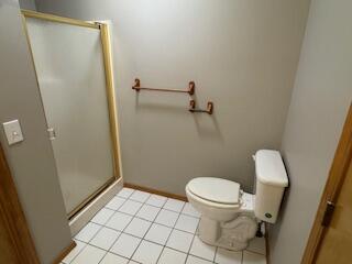 bathroom featuring baseboards, a stall shower, toilet, and tile patterned floors