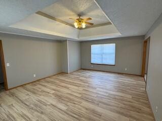 spare room with a tray ceiling and wood finished floors