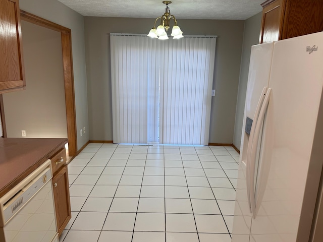 unfurnished dining area with a chandelier, a textured ceiling, baseboards, and light tile patterned floors