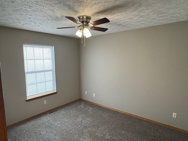 spare room with ceiling fan, a textured ceiling, carpet flooring, visible vents, and baseboards