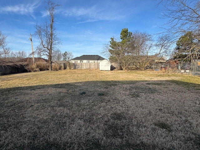 view of yard with an outbuilding, fence, and a storage shed