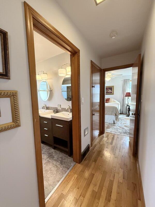 hall featuring light wood-style floors, baseboards, and a sink