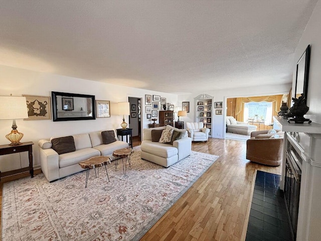 living area with a fireplace, a textured ceiling, and wood finished floors