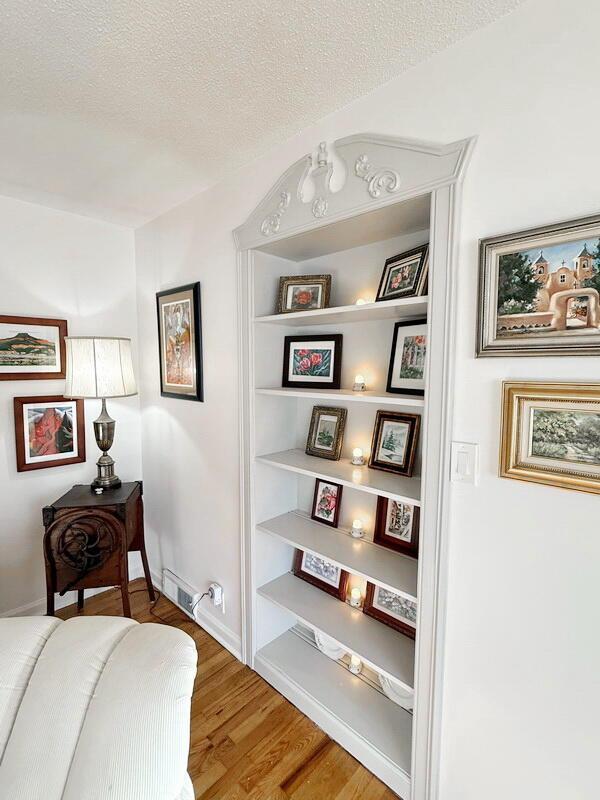 living area featuring a textured ceiling, baseboards, and wood finished floors