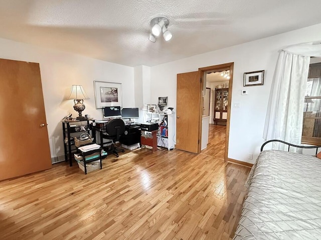 home office featuring a textured ceiling, light wood-type flooring, and baseboards