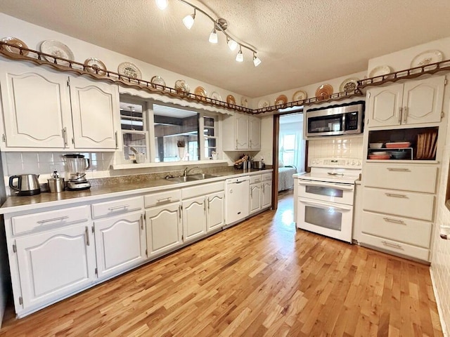 kitchen with backsplash, light wood-style floors, a sink, a textured ceiling, and white appliances