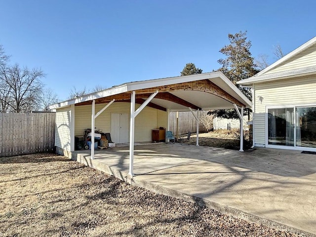 view of parking with driveway, fence, and a carport