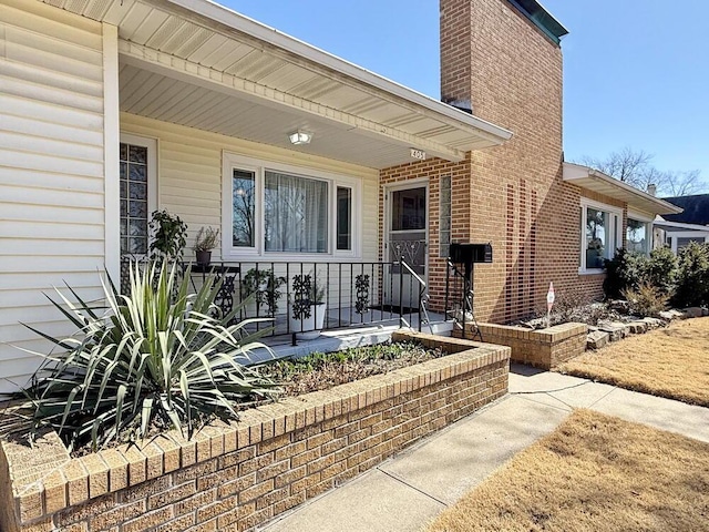 property entrance with a chimney and brick siding