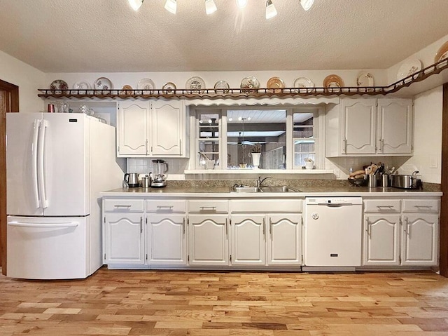 kitchen with a textured ceiling, white appliances, light wood-type flooring, and a sink