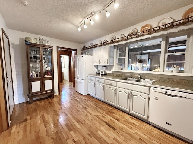 kitchen featuring white appliances, light wood-style flooring, a textured ceiling, and a sink