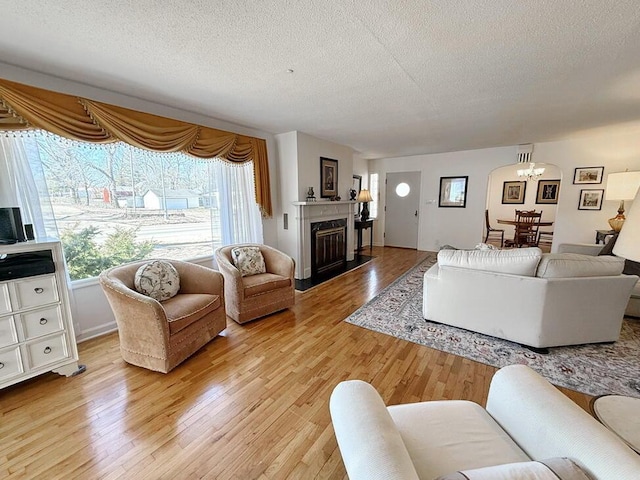 living area featuring a textured ceiling, a high end fireplace, and light wood-style floors