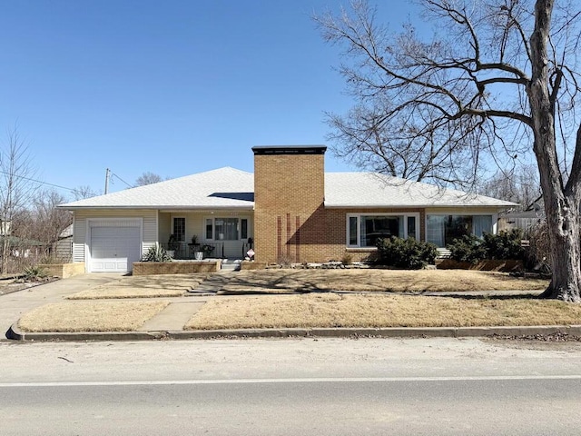 view of front of home featuring a garage, concrete driveway, brick siding, and a chimney