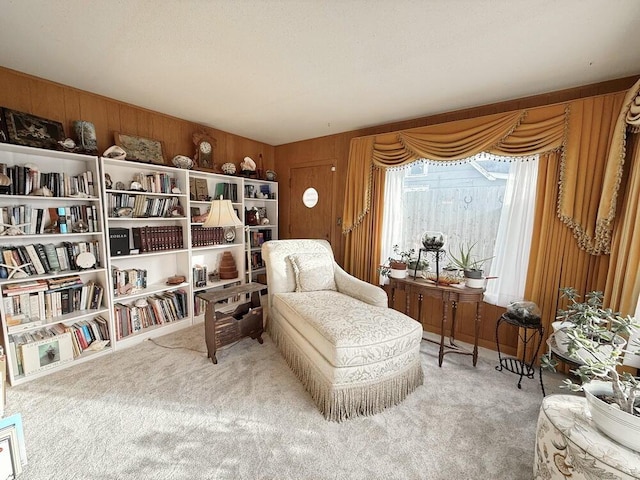 living area featuring carpet and wooden walls