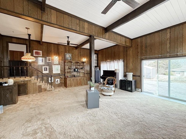 carpeted living room featuring beam ceiling, ceiling fan, and wooden walls