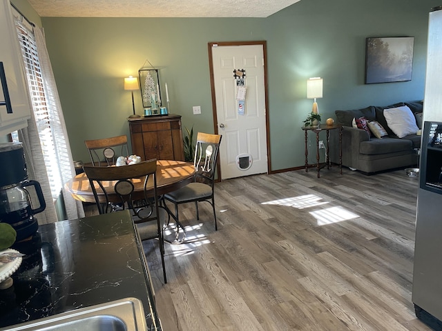 dining room featuring a textured ceiling, baseboards, and wood finished floors